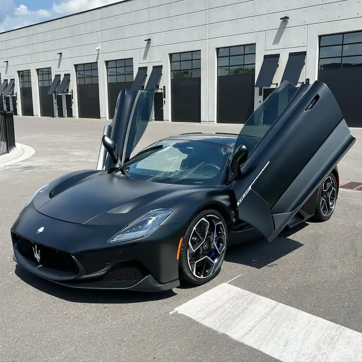 A matte black Maserati MC20 with its doors raised, finished by Brick's
