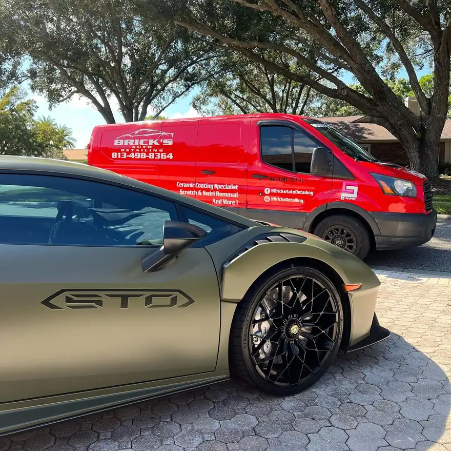 A green Lamborghini Huracán STO beside Brick's branded service van